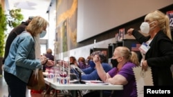 FILE - Poll workers help voters check in at Lincoln Center on the first day of early voting in New York, Oct. 23, 2021.