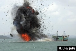 FILE - Parts of boats fly into the air as foreign fishing boats are blown up by Indonesian Navy off Batam Island, Indonesia on Monday, Feb. 22, 2016. Officials sank tens of fishing boats caught operating illegally in Indonesian waters. (AP Photo/M. Urip, File)