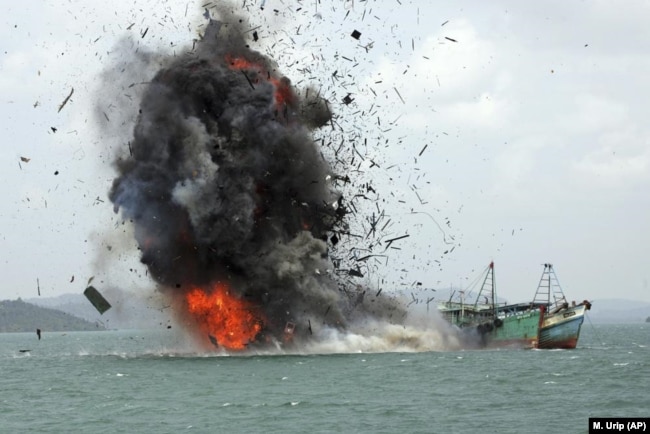 FILE - Parts of boats fly into the air as foreign fishing boats are blown up by Indonesian Navy off Batam Island, Indonesia on Monday, Feb. 22, 2016. Officials sank tens of fishing boats caught operating illegally in Indonesian waters. (AP Photo/M. Urip, File)