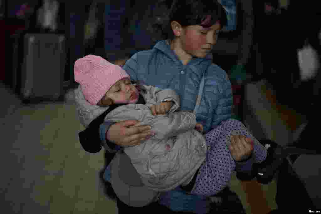Ukrainian refugees Tania, 2, and Galina, 11, wait in the ticket hall at Przemysl Glowny train station, after fleeing the Russian invasion of Ukraine, in Poland.