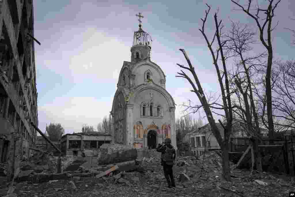 A Ukrainian serviceman takes a photograph of a damaged church after shelling in a residential district in Mariupol.