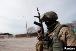 A service member of pro-Russian troops stands in a street during Ukraine-Russia conflict in the besieged southern port city of Mariupol, Ukraine, March 31, 2022.