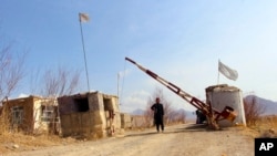 FILE- Taliban soldier stands guard at the entrance gate of Mes Aynak valley, southwest of Kabul, Afghanistan, March 2, 2022.