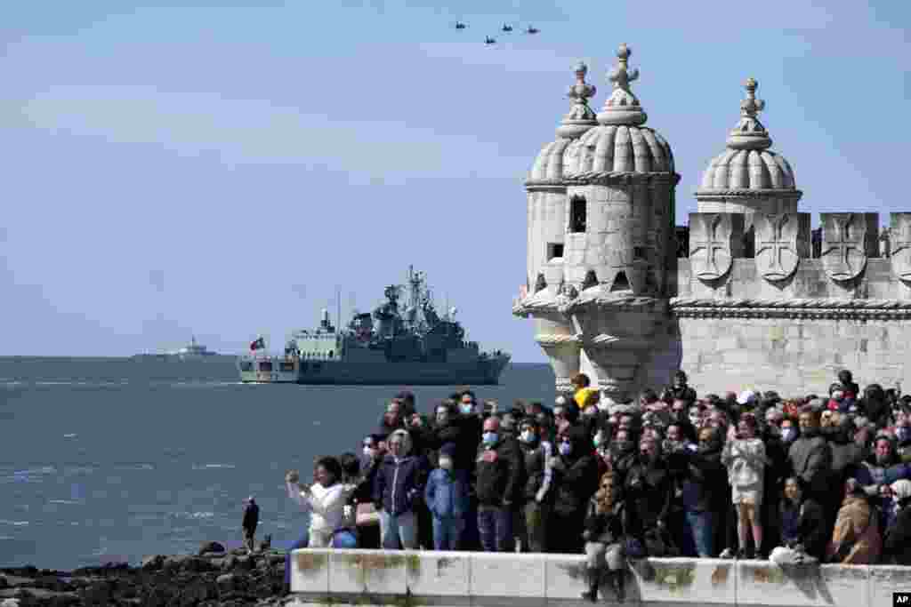 People watch Navy ships, sail boats and military aircraft pass along the Tagus River in Lisbon during celebrations of the 100th anniversary of the first aerial crossing of the South Atlantic.