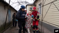 Associated Press photographer Evgeniy Maloletka helps a paramedic to transport a woman injured during shelling in Mariupol, eastern Ukraine, March 2, 2022.