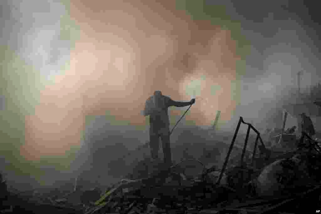 Neighbors try to extinguish the fire of a house, destroyed after a Russian attack in Kharkiv, Ukraine.