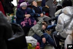 FILE - People who fled the war from neighboring Ukraine sleep at the Przemysl train station in Przemysl, Poland, March 9, 2022.