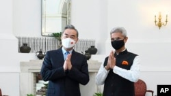 In this photo provided by Indian Foreign Minister S. Jaishankar's Twitter handle, Jaishankar and his Chinese counterpart Wang Yi greet the media before their meeting in New Delhi, India, March 25, 2022.