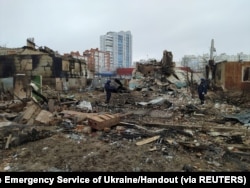 Members of Ukrainian emergency services stand amid rubble in Chernihiv as Russia's invasion of Ukraine continues, March 9, 2022.
