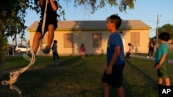 FILE - Children play in the yard of a community boxing club Aug. 19, 2021, in Somerton, Ariz.