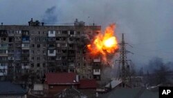 An explosion is seen in an apartment building after a Russian army tank fires in Mariupol, Ukraine, March 11, 2022.