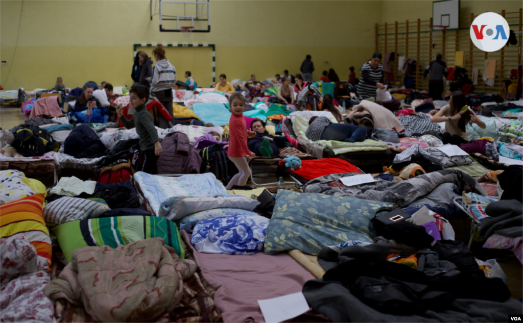 En el gimnasio del centro escolar se han colocado camas plegables para que los refugiados puedan descansar. Mientras algunos adultos reponen fuerzas, los niños juegan entre los catres.&nbsp;