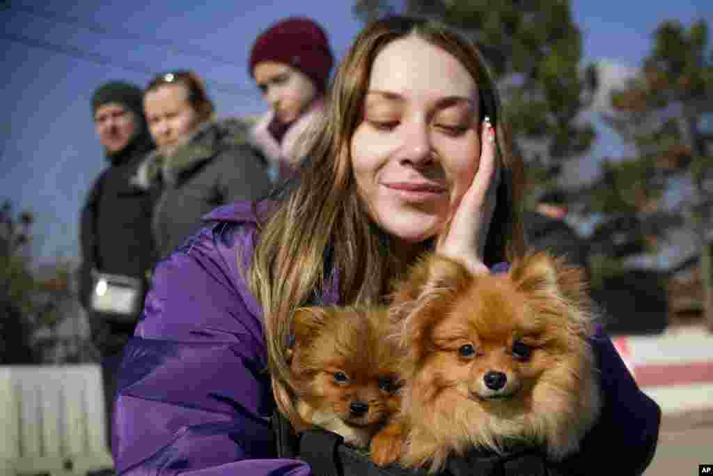 A refugee fleeing the war from neighboring Ukraine holds her dogs after crossing the border, at the Romanian-Ukrainian border, in Siret, Romania.
