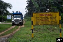 FILE - A truck drives along a high pressure oil pipeline in Ejamah-Ebubu, Ogoniland, in Rivers State, southern Nigeria, Aug. 23, 2021.