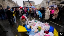 A demonstrator covers baby dolls representing victims of Russia's ongoing war with the Ukraine flag during a rally in Budapest, Hungary, April 2, 2022, ahead of Sunday's election.