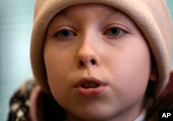 Annamaria Moslovska, a ten-year-old from Kharkiv, eastern Ukraine, speaks in a waiting room at the train station in Zahony, Hungary, Monday, March 7, 2022. (AP Photo/Darko Vojinovic)