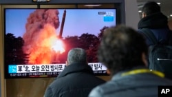 Ljudi prate televizijski program vijesti i arhivsku fotografiju lansiranja rakete Sjeverne Koreje, na železničkoj stanici u Seulu, 20. marta 2022.