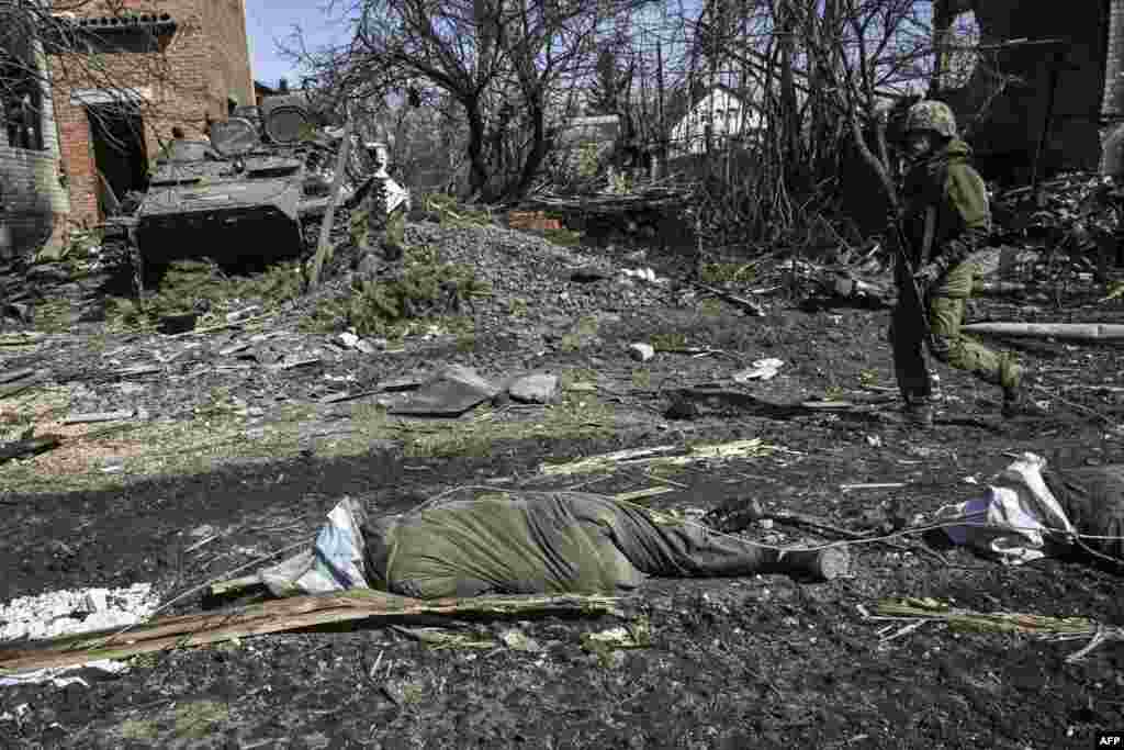 A man walks past a body of a Russian soldier laying on the ground after the Ukranian troops retaking the village of Mala Rogan, east of Kharkiv.