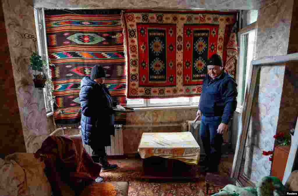 Local residents cover broken windows with rugs in an apartment damaged by shelling during Ukraine-Russia conflict in the separatist-controlled town of Makeyevka (Makiivka) outside Donetsk, March 16, 2022.