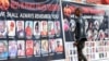 FILE - A man walks toward a banner depicting people allegedly killed by Ugandan security personnel, at the National Unity Platform party offices, in the Kamwokya suburb of Kampala, Uganda, March 21, 2022.