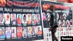 A man walks towards a banner depicting people allegedly killed by Ugandan security personnel, at the National Unity Platform party offices, in the Kamwokya suburb of Kampala, Uganda, March 21, 2022.