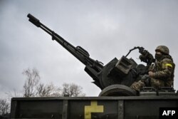 A Ukrainian soldier keeps position sitting on a ZU-23-2 anti-aircraft gun at a frontline, northeast of Kyiv, March 3, 2022.