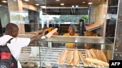 Une femme vend du pain dans une boulangerie à Abobo, une commune d'Abidjan, le 24 mars 2022. (Photo Issouf SANOGO / AFP)