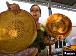 Seorang perempuan menjual roti tradisional Uzbekistan (patir) di dekat kota Kokand, 30 Agustua 2012. (REUTERS/Shamil Zhumatov)