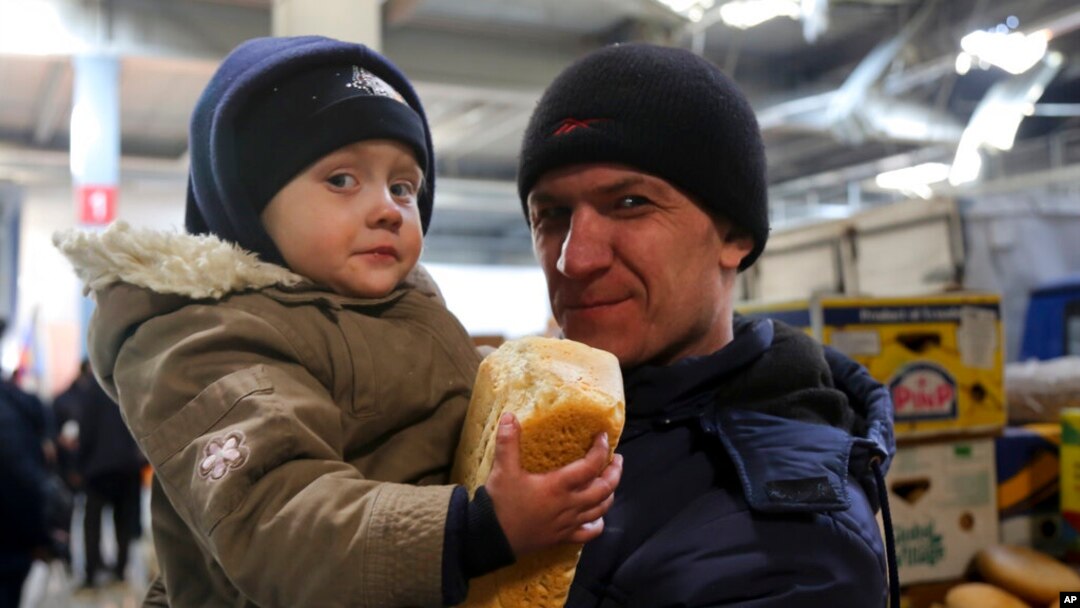 A man and his child wait to get food and drinking water at a supermarket in the territory under the Government of the Donetsk People's Republic control, on the outskirts of Mariupol, Ukraine, March 24, 2022. 