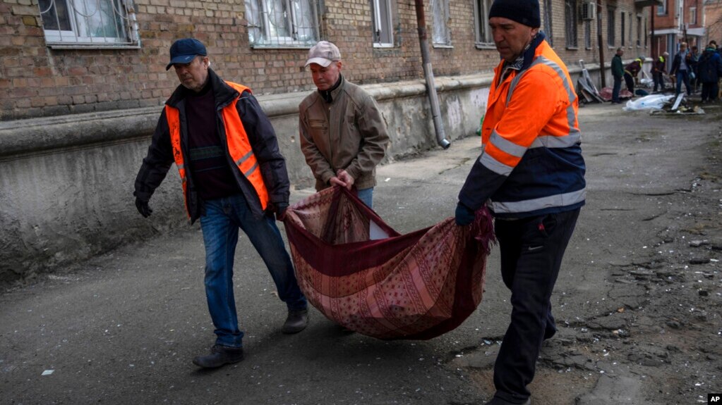 2022年3月23日，在乌克兰基辅，邻居们从被炮击的公寓里搬出被打碎的窗户玻璃碎片。（美联社）(photo:VOA)