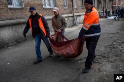 Neighbors carry pieces of broken window from apartments damaged by shelling, in Kyiv, Ukraine, March 23, 2022.