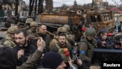 Ukraine's President Volodymyr Zelenskiy speaks to the media as he is surrounded by Ukrainian servicemen in Bucha, outside Kyiv, April 4, 2022.