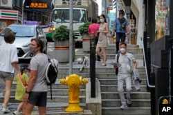 Warga mengenakan masker saat beraktifitas di Hong Kong, 15 Maret 2022. (AP/Kin Cheung)