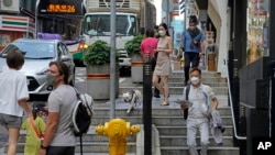 People wearing face masks walk alone a street in Hong Kong, March 15, 2022. Hong Kong on Monday reported 26,908 new coronavirus cases and 249 related deaths in its latest 24-hour period.