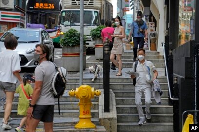 Warga mengenakan masker saat beraktifitas di Hong Kong, 15 Maret 2022. (AP/Kin Cheung)