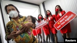 Sejumlah pramugari menyambut penumpang dari Jakarta yang baru tiba di Bandara Internasional Kuala Lumpur 2 (KLIA), Selangor, Malaysia, 1 April 2022. (Foto: Hasnoor Hussain/Reuters)