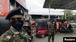 Para tentara Sri Lanka tampak berjaga di pom bensin milik Ceylon Petroleum di Colombo, Sri Lanka, pada 22 Maret 2022. Mereka dihadirkan untuk membantu pendistribusian minyak di tengah krisis bahan bakar yang terjadi di negara itu. (Foto: Reuters/Dinuka Liyanawatte)