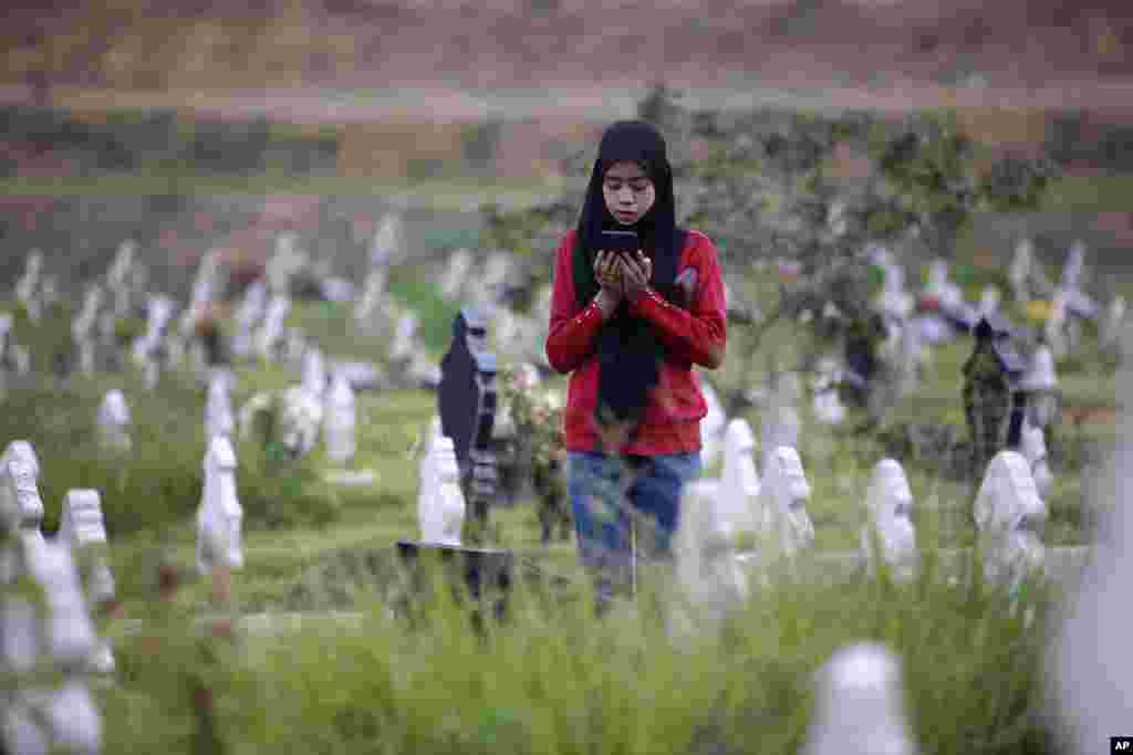 A Muslim woman prays at the grave of a relative at a cemetery reserved for those who died of COVID-19, in Medan, North Sumatra, Indonesia.