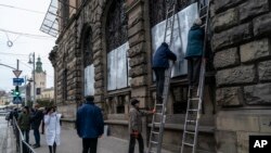 FILE - People cover the windows Museum of Ethnography with metal plates in Lviv, western Ukraine, March 2, 2022.