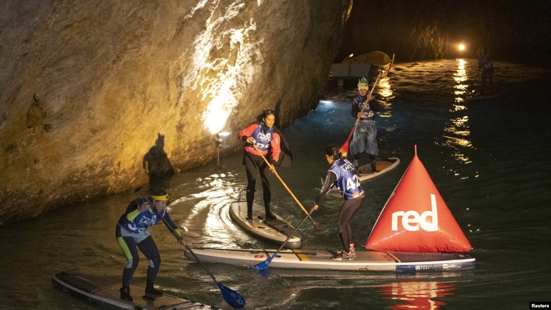 Para peserta "BAT Race" dari Tur Danau Alpine, bertanding Stand Up Paddle (SUP) di danau bawah tanah terbesar di Eropa, St-Leonard dekat Sion, Swiss, 12 Maret 2022. (REUTERS/Denis Balibouse)