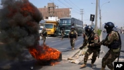 4일 페루 수도 리마 외곽에서 시위진압경찰이 운송 노동자 시위대가 타이어 더미에 붙인 불을 끄고 있다.
