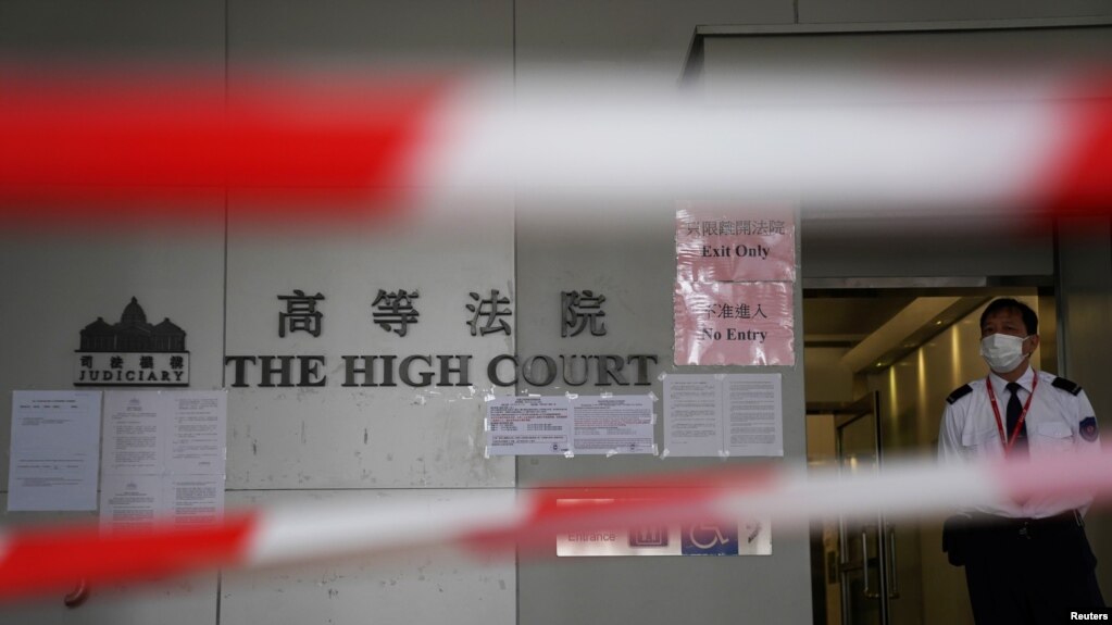 FILE - A guard stands behind cordons before a hearing at the High Court in Hong Kong, March 11, 2021.