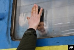FILE - A child says goodbye to a relative looking out the window of a train carriage waiting to leave Ukraine for western Ukraine at the railway station in Kramatorsk, eastern Ukraine, on Feb. 27, 2022.