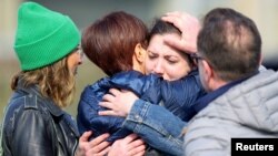 Women embrace each other after a vehicle drove into a group of Belgian carnival performers who were preparing for a parade in the village of Strepy-Bracquegnies, Belgium, March 20, 2022.