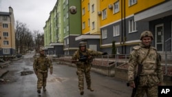 Ukrainian soldiers play with a ball in Irpin, on the outskirts of Kyiv, Ukraine, April 2, 2022, following a retreat of Russian troops from the region.