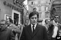 Aktor Prancis Alain Delon berjalan-jalan sebentar dari lokasi syuting film barunya, "The Sicilians," saat jeda syuting di pusat kota Roma, 27 Maret 1969. (Foto: AP)