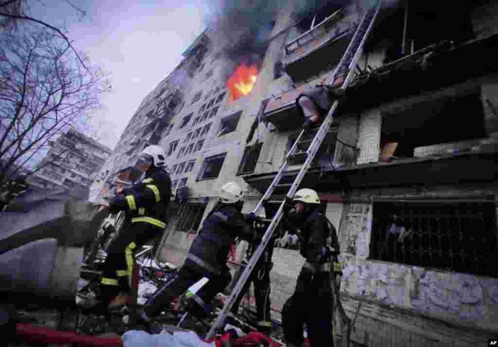In this photo released by Ukrainian State Emergency Service, firefighters work at an apartment building hit by shelling in Kyiv, March 14, 2022.&nbsp;