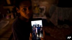 FILE - María Carla Milan Ramos shows a photo on her mobile phone of her husband with his siblings, who are all in prison accused of participating in the recent protests against the government, at their home in La Guinera neighborhood of Havana, Cuba, Jan.