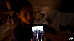 FILE - María Carla Milan Ramos akionyesha ndugu zake waliohukumiwa kifungo kwa tuhuma za kushiriki katika maandamanao yaliyokuwa yanapinga serikali, wakiwa nyumbani kwao huko La Guinera karibu na Havana, Cuba, (AP Photo/Ramon Espinosa, File)