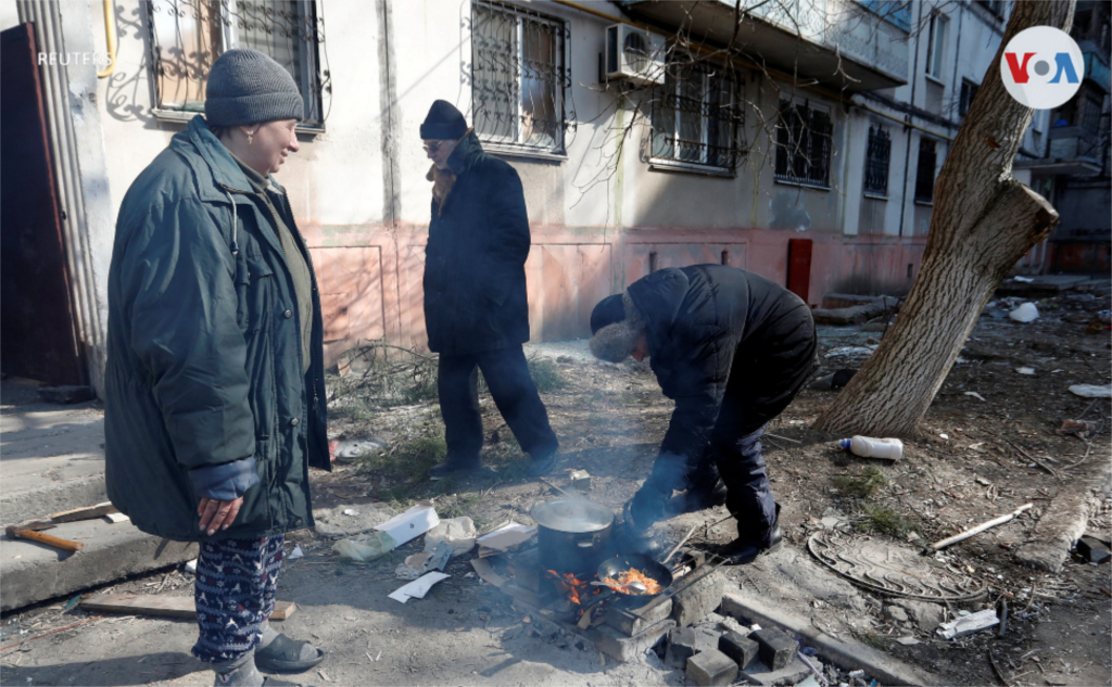 Aunque muchos han abandonado la ciudad, otros permanecen en ella. En la foto, locales preparan alimentos afuera de un edificio residencial.